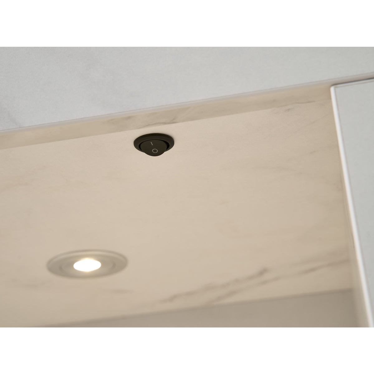 Close up of the downlight and switch in the Acantha chamber kit in white marble effect