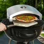 Artisan pizza oven insert on a kettle charcoal barbecue with a pizza on a peel