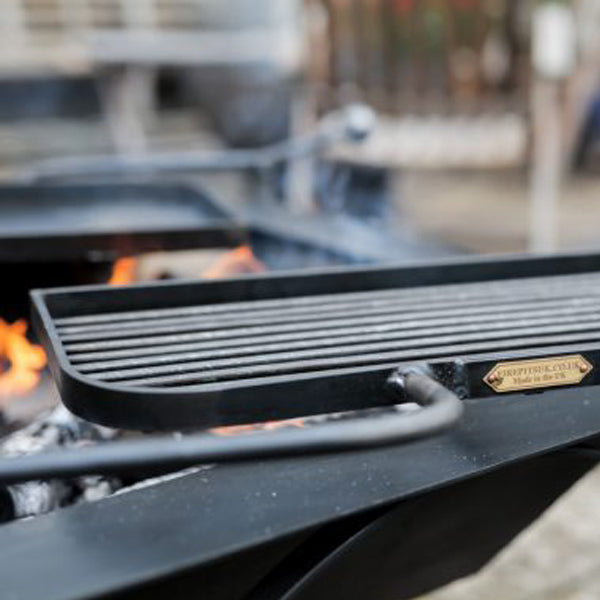 Close-up of a Box D swing arm BBQ rack with its half plate, half bar cooking surface over the fire