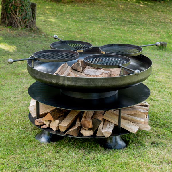 Ring of Logs 120 fire pit with four swing arm BBQ racks in a garden