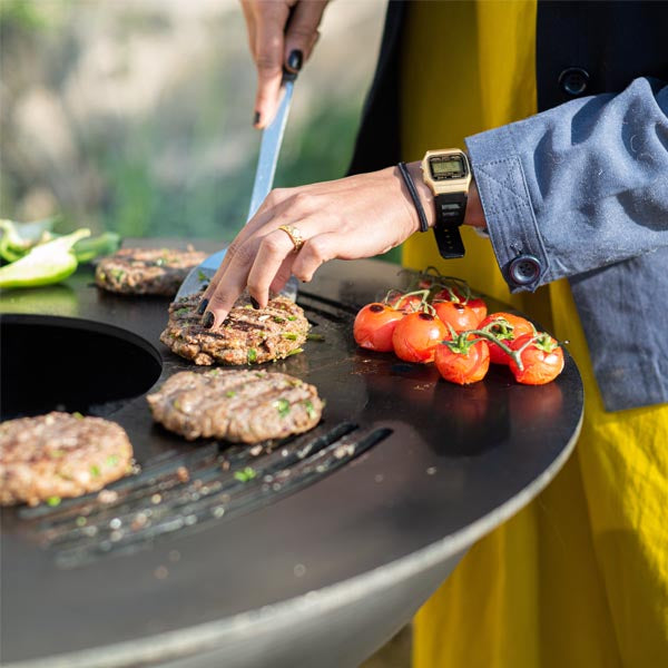 Burgers cooking on the flat plate of the Plancha Fire Pit ring