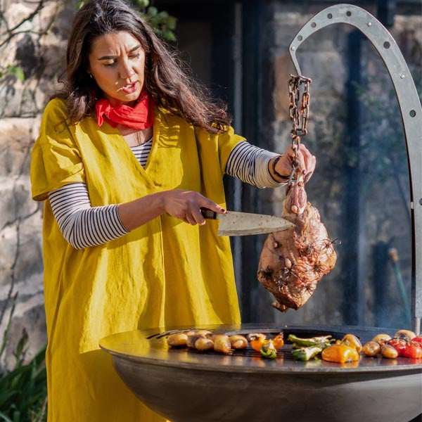 Carving a leg of lamb cooked over the Plancha Fire Pit