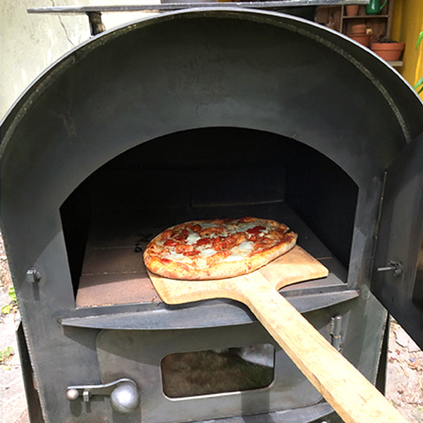 Pizza being loaded into the Tall Pizza Oven with a paddle
