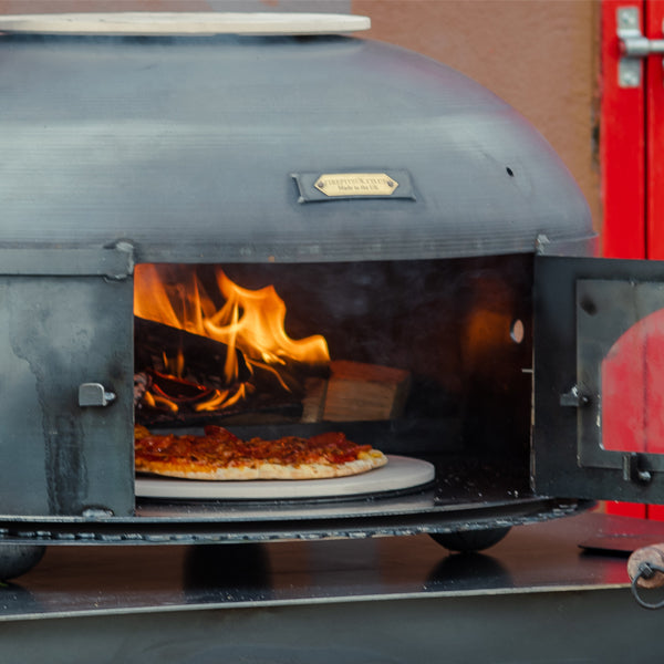 Dome Oven with the door open and a pizza inside