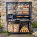 Firepits UK Asado Maximo fire table lit with food on the grill, rotisserie and hanging racks