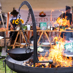 Hanging arm holding a cooking pot over a lit fire pit