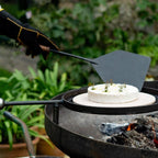Fire pit paddle lifting a camembert on a swing arm rack
