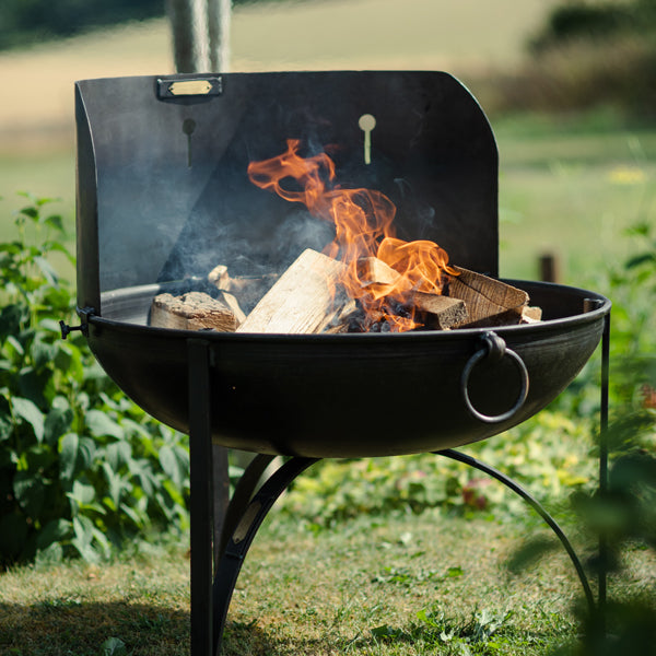 Wind shield on a lit Plain Jane fire pit in a garden